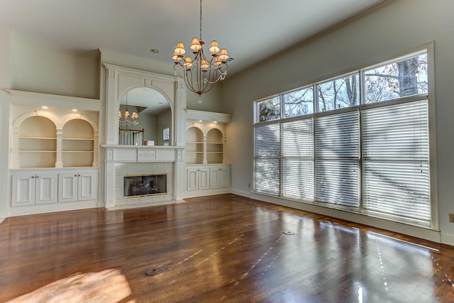 unfurnished living room with built in features, a wealth of natural light, and an inviting chandelier