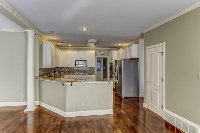 kitchen with kitchen peninsula, decorative backsplash, light stone counters, stainless steel appliances, and white cabinetry