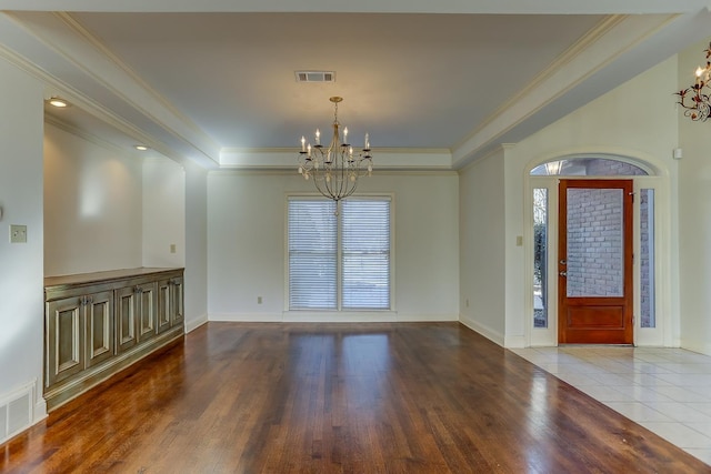 tiled foyer entrance with a raised ceiling, a wealth of natural light, ornamental molding, and an inviting chandelier