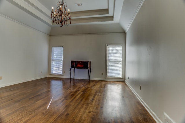 interior space featuring a raised ceiling, ornamental molding, dark hardwood / wood-style floors, and a notable chandelier