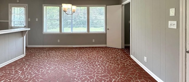 unfurnished dining area featuring a notable chandelier and wood walls