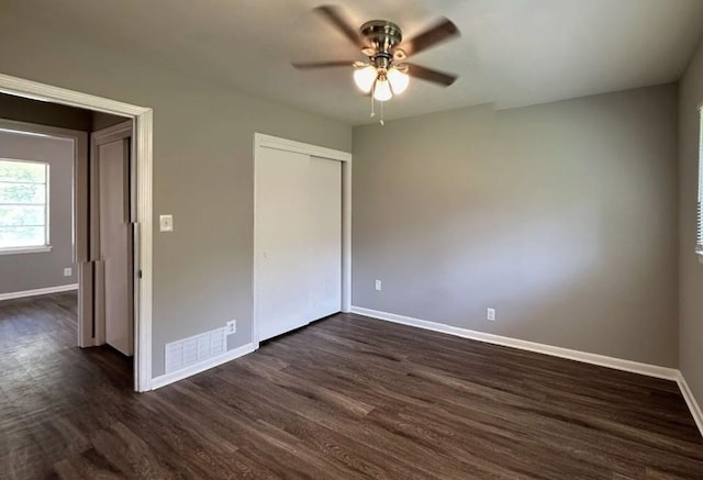 unfurnished bedroom with ceiling fan, dark wood-type flooring, and a closet