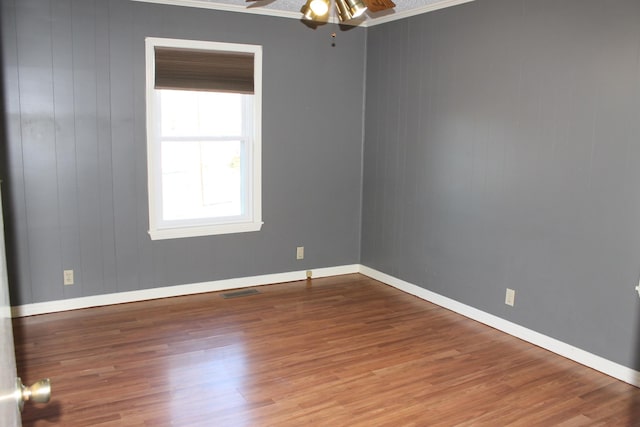 spare room featuring ceiling fan, wood-type flooring, and crown molding