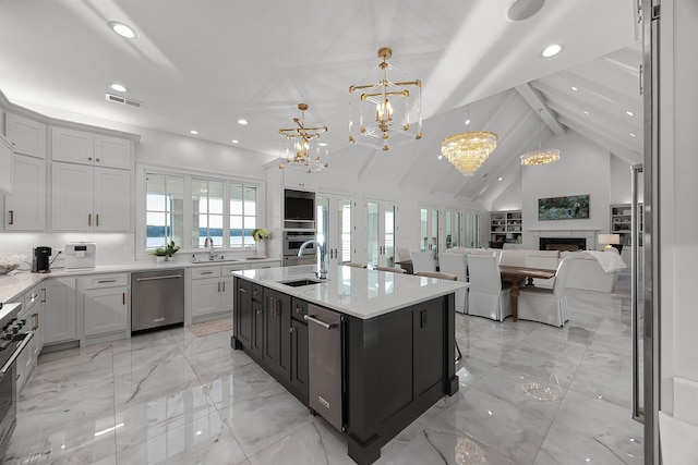 kitchen with an inviting chandelier, white cabinets, an island with sink, appliances with stainless steel finishes, and decorative light fixtures