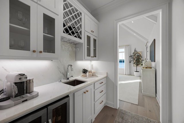 kitchen with light hardwood / wood-style floors, white cabinetry, crown molding, and sink