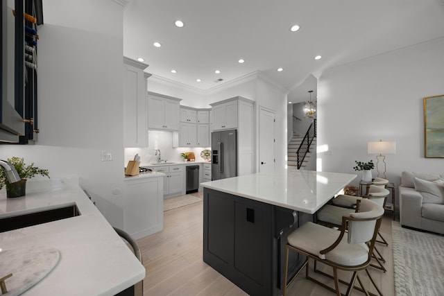 kitchen with sink, an inviting chandelier, stainless steel fridge, a breakfast bar area, and light wood-type flooring