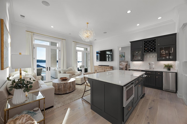 kitchen featuring french doors, sink, hanging light fixtures, a kitchen island, and ornamental molding