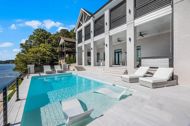 view of pool featuring ceiling fan, a patio area, and a water view