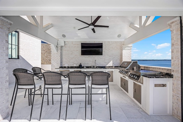 view of patio featuring an outdoor kitchen, a water view, an outdoor wet bar, and a grill