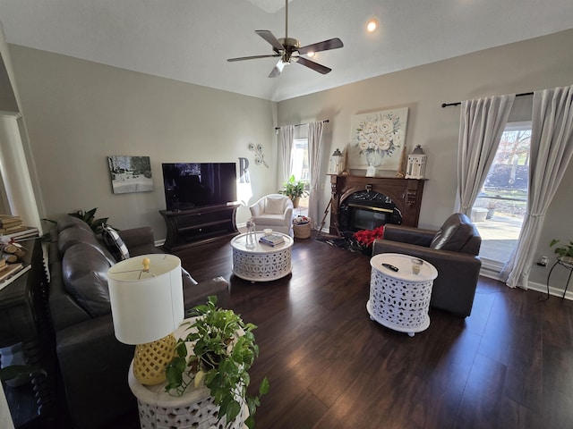 living room featuring a premium fireplace, dark hardwood / wood-style flooring, ceiling fan, and vaulted ceiling