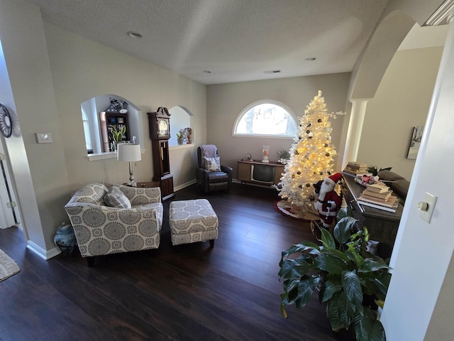 interior space featuring a textured ceiling, dark hardwood / wood-style flooring, and ornate columns