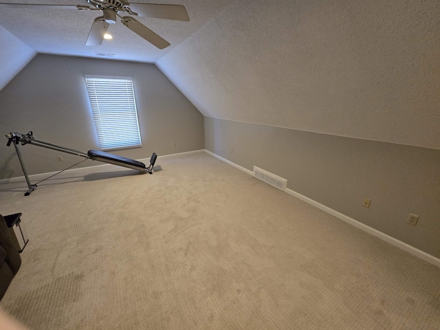 additional living space with ceiling fan, light colored carpet, a textured ceiling, and vaulted ceiling