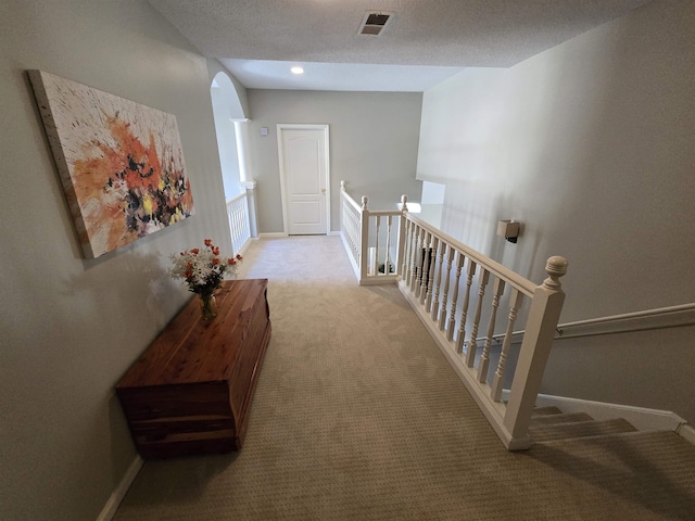 hall with a textured ceiling and light carpet