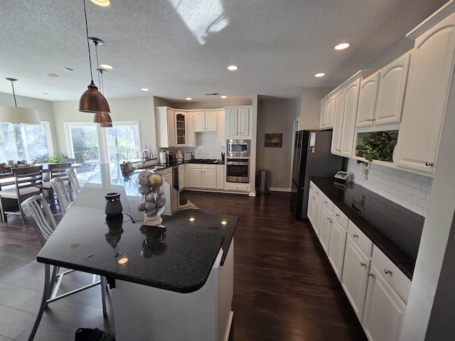 kitchen featuring tasteful backsplash, white cabinetry, sink, and decorative light fixtures