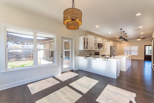 kitchen featuring kitchen peninsula, appliances with stainless steel finishes, sink, pendant lighting, and white cabinetry