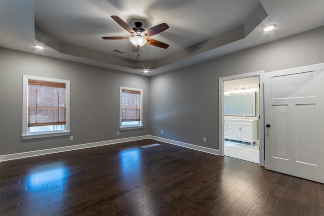 empty room featuring sink, a tray ceiling, ceiling fan, and dark hardwood / wood-style floors