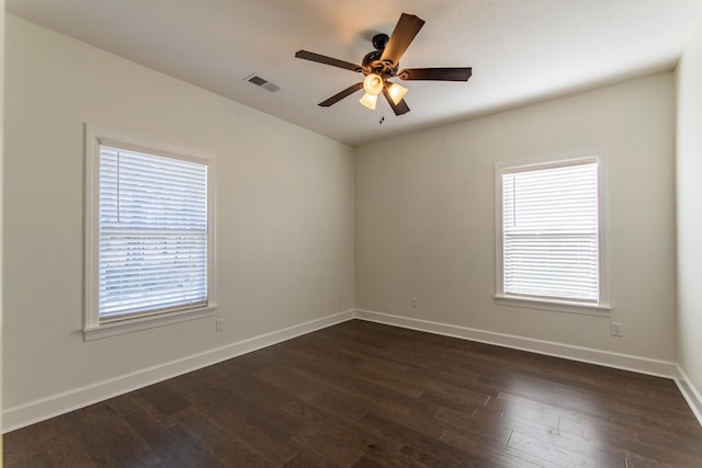 spare room featuring a wealth of natural light, ceiling fan, and dark hardwood / wood-style floors