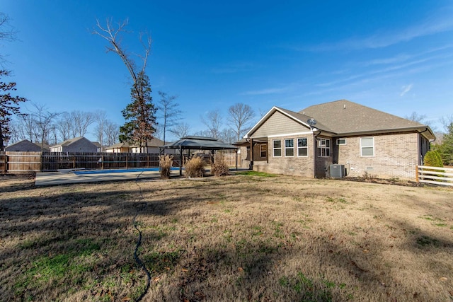 rear view of house with a gazebo, central AC, a yard, and a pool