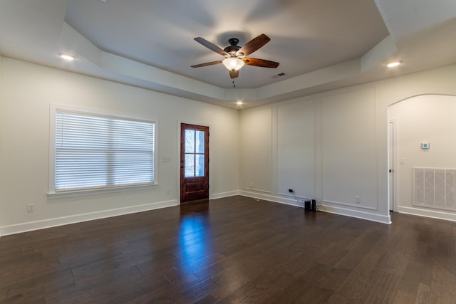 interior space with dark hardwood / wood-style flooring, a raised ceiling, and ceiling fan