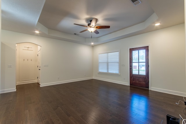 unfurnished room with a raised ceiling, ceiling fan, and dark wood-type flooring