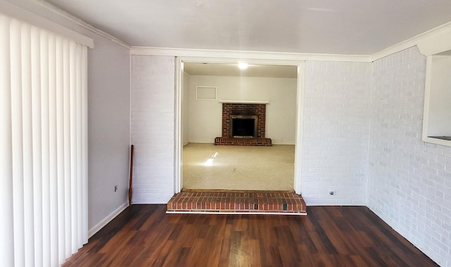 spare room with crown molding, a fireplace, brick wall, and wood finished floors