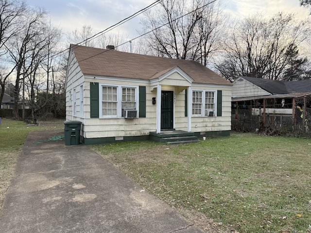 bungalow-style home with cooling unit and a front lawn