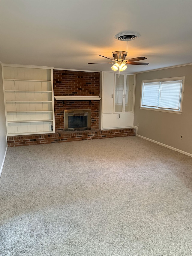 unfurnished living room featuring a brick fireplace, ceiling fan, crown molding, and carpet flooring