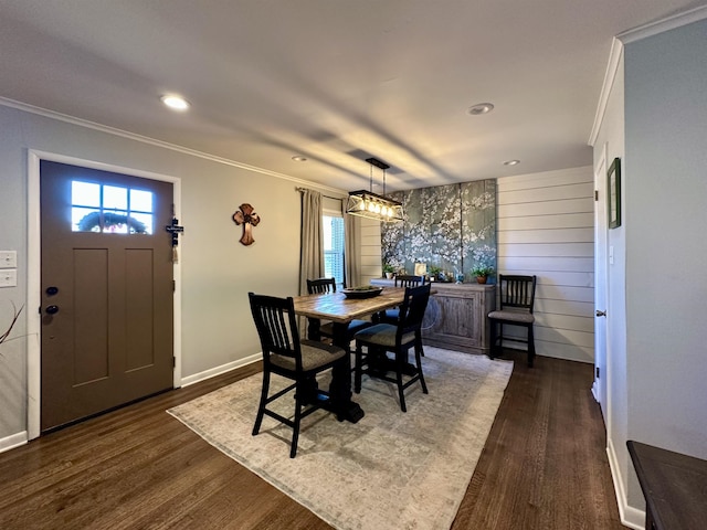 dining room featuring a chandelier, dark wood-type flooring, crown molding, and wood walls