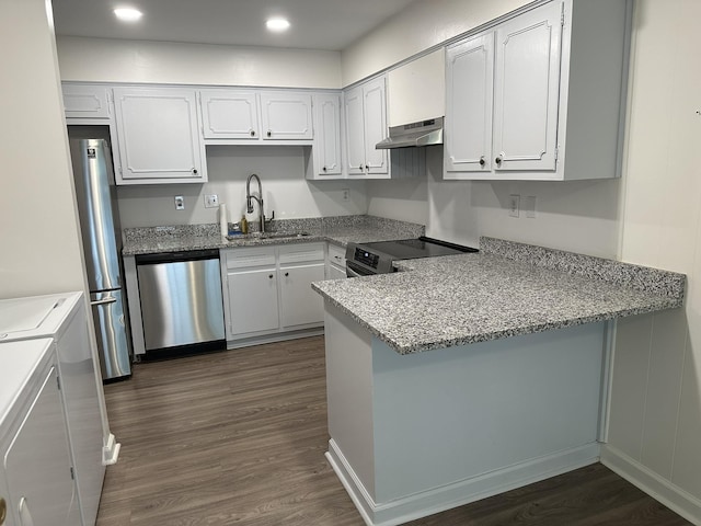 kitchen with stainless steel appliances, washer and clothes dryer, sink, white cabinets, and range hood