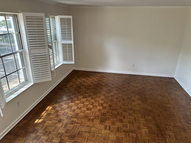 empty room with dark parquet flooring, a healthy amount of sunlight, and ornamental molding