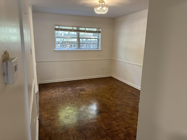 empty room with dark parquet floors and a chandelier