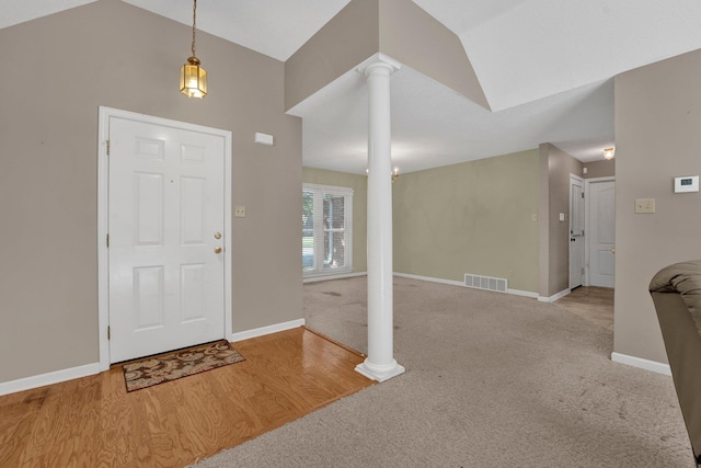 foyer with hardwood / wood-style flooring, lofted ceiling, and decorative columns