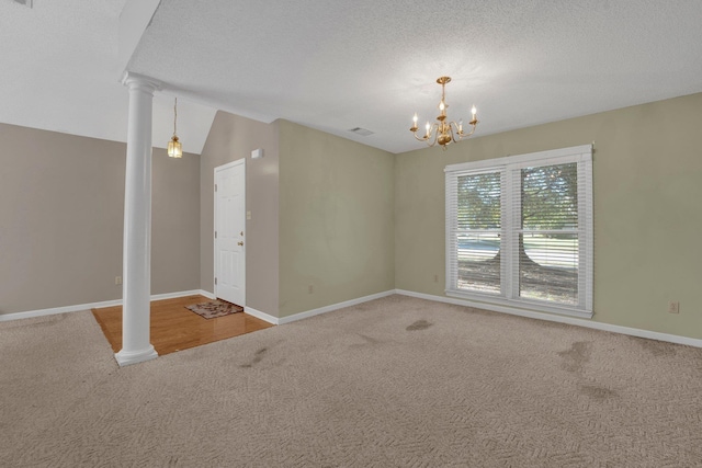 unfurnished room featuring a chandelier, carpet floors, ornate columns, and lofted ceiling