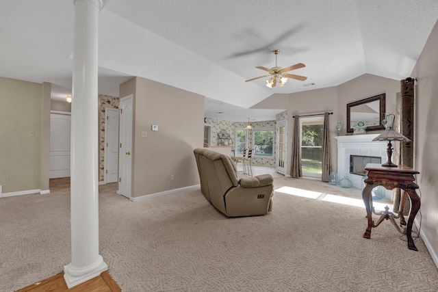 living room with vaulted ceiling, ceiling fan, ornate columns, light colored carpet, and a tiled fireplace