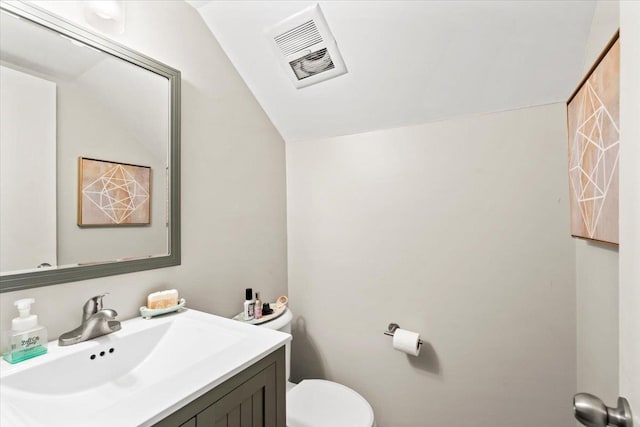 bathroom featuring vanity, toilet, and vaulted ceiling