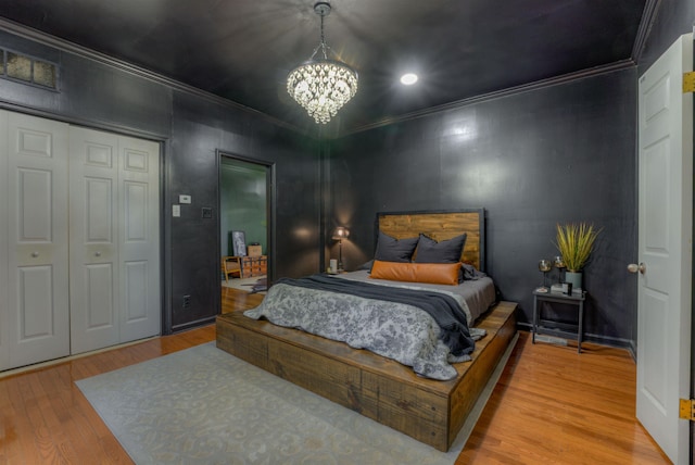 bedroom featuring ornamental molding, a closet, a chandelier, and light wood-type flooring