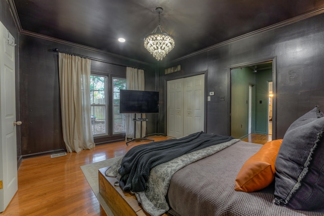 bedroom with a closet, light wood-type flooring, ornamental molding, and a chandelier