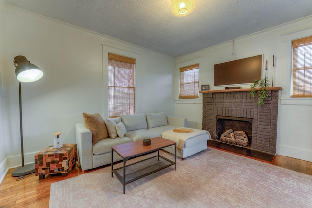 living room featuring a textured ceiling, hardwood / wood-style flooring, a brick fireplace, and ornamental molding