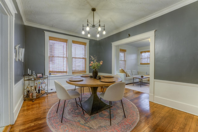 dining room with a chandelier, crown molding, wood-type flooring, and a textured ceiling