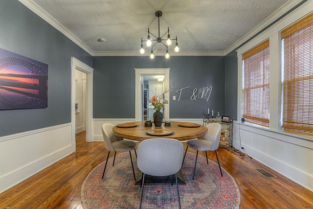 dining area featuring a textured ceiling, ornamental molding, and dark wood-type flooring