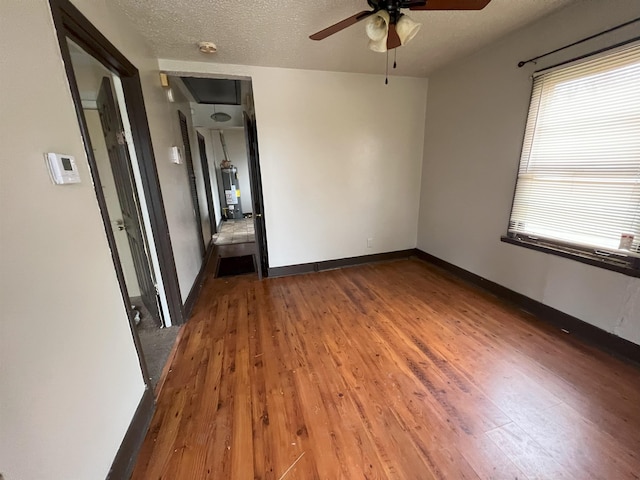 empty room with a textured ceiling, a wealth of natural light, and dark wood-type flooring