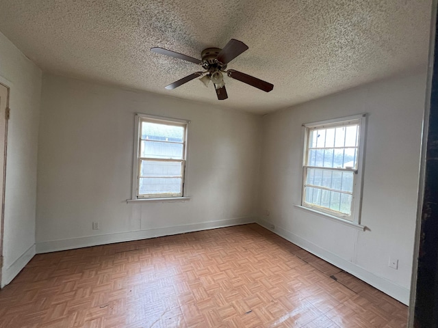 empty room with ceiling fan, a healthy amount of sunlight, a textured ceiling, and light parquet flooring