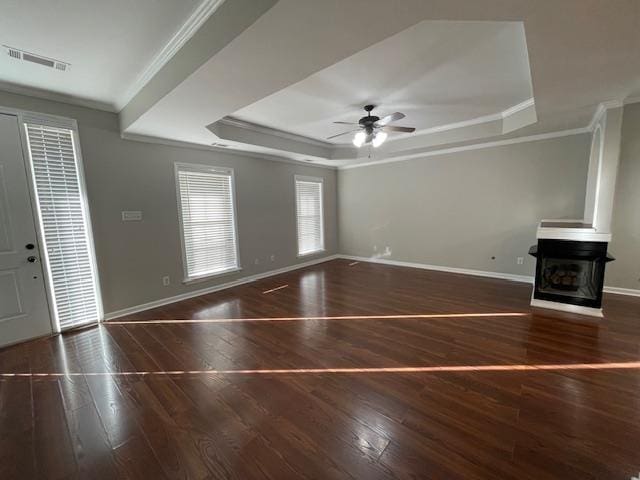 unfurnished living room with a multi sided fireplace, a raised ceiling, ceiling fan, ornamental molding, and dark hardwood / wood-style flooring