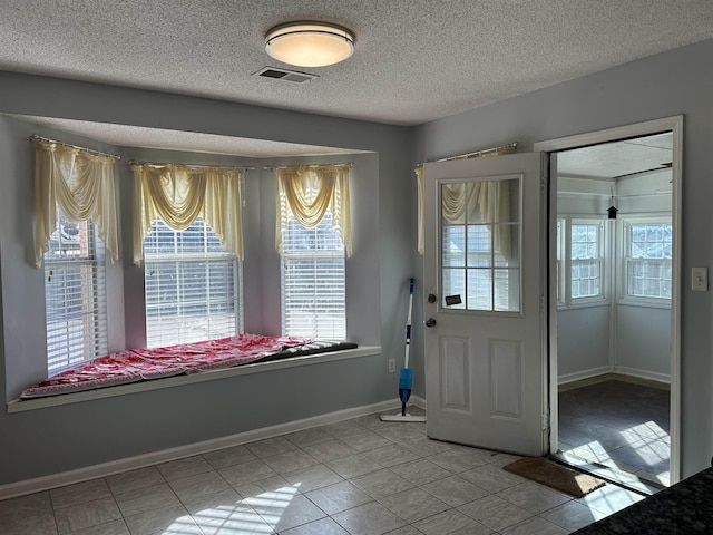 doorway to outside featuring tile patterned flooring and a textured ceiling