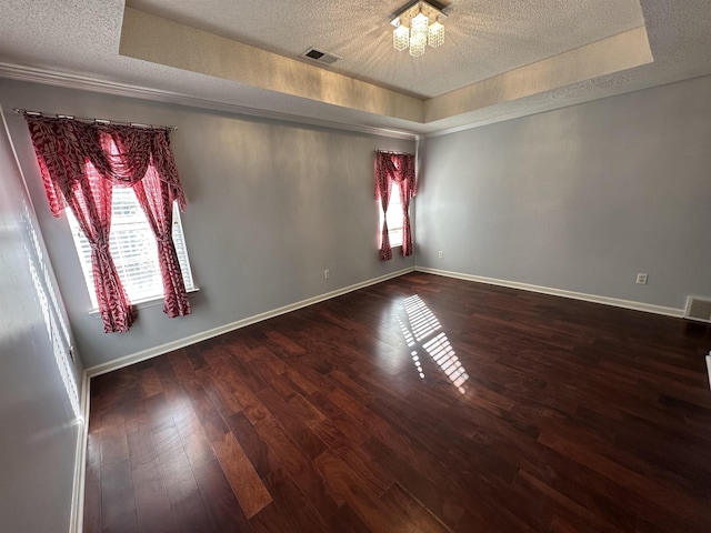 unfurnished room with a healthy amount of sunlight, a raised ceiling, a notable chandelier, and wood-type flooring