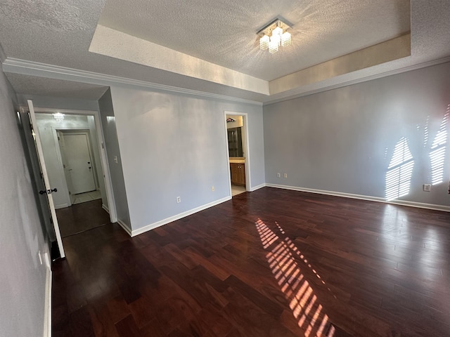 empty room with dark hardwood / wood-style flooring, a textured ceiling, and a tray ceiling