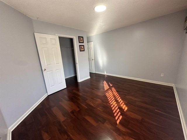 unfurnished bedroom with a closet, dark hardwood / wood-style flooring, and a textured ceiling