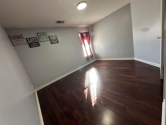 unfurnished room with dark hardwood / wood-style flooring and a textured ceiling