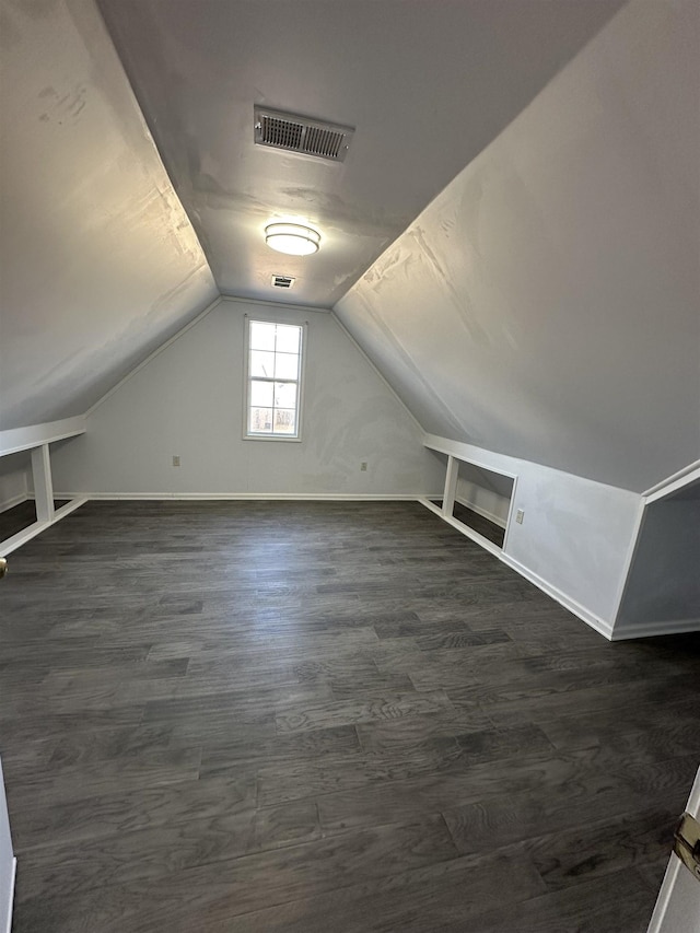 additional living space with built in features, dark wood-type flooring, and lofted ceiling