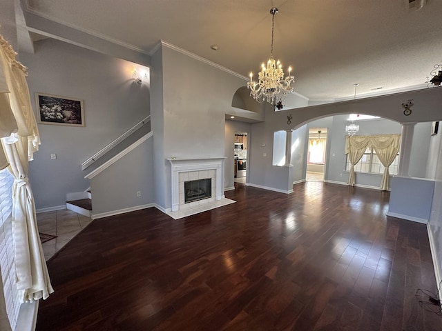 unfurnished living room with hardwood / wood-style floors, a chandelier, crown molding, and a tiled fireplace